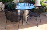 Four Woodard patio chairs. Round heavy glass top table with undulating stainless steel base.