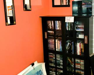 Modern style glass-front storage cabinet full of new and used music CDs and DVD / Blu-ray movies