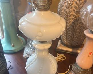 This is a 1940s to 1950s white milk glass beaded swirl table lamp with brass finish accents.