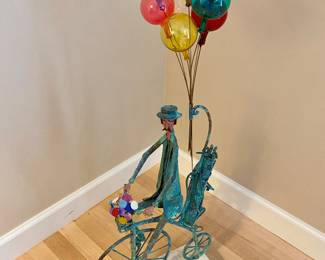 Jim Lewk sculpture metal artist.  Colorful piece is made of copper with golf clubs, basket of flowers and hand blown glass balloons signed