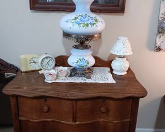 Oak dresser, vintage alarm clocks, gone with the wind lamp, piano picture.