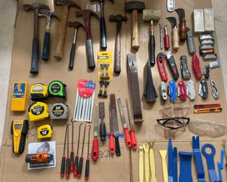 Hammers, mallets, crowbar, wedge, files, tape measures, stud finders, safety glasses, box cutters, razor blades, folding knives, plastic tools in lower right corner