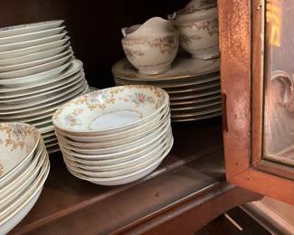 Close up of items in previous china cabinet - bottom shelf - set of dishes