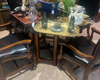 Octoganal glass top table great for a game table or breakfast table. 4 leather chairs on casters.