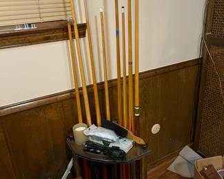 Pool table and eight pool cues with wooden cue holder.