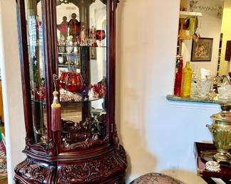 Heavily carved slender curio cabinet.