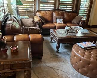 Plush leather and wood matching sofa and love seat, large elegantly tooled coffee table with marble inserts, and tufted leather ottoman. Matching side table.