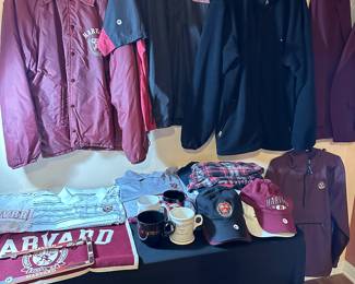 Table full of Harvard university, jackets, shirts, and hats
