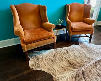 Orange velvet McAfee wing back chairs.  Cow hide on floor also for sale.