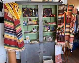 Rustic gray multi door cupboard with assorted Native American  blankets