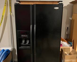Black side by side fridge, Whirlpool brand. White cabinet 
