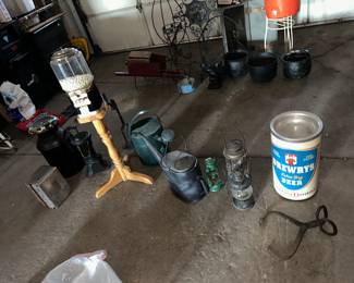 FRONT ROW: starting on the left... milk can. paper towel wall dispenser, water pump, candy dispensing machine w/ key, bottle can unit, sprinkling cans, 3 lanterns, hay/ice tongs and Drewrys beer can. BACK ROW: wheel barrow w/ a proper description of the box holding square headed nails, various black  yard holders and plant stands, cement squirrel, 3 witches cauldrons and a carpenters wood tool box in the far back.