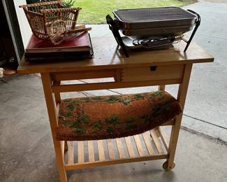 This outdoor serving cart can hold more than the small grill and a miniature hay cart.  You'll need to ask to see this piece in person.
