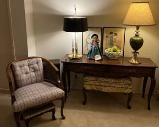 A mixed set of lamps adorn this side table.  A nearby chair and ottoman set help make this a cozy scene.  