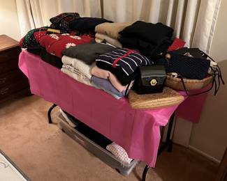 Some of the clothing items are folded and on this table.