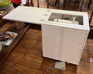 In this photograph, the Pfaff hobbymatic 919-1 sewing machine and cabinet.  The cabinet's hardware raises and lowers the machine within the cabinet.  