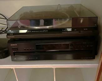 There is a stereo set sitting in an entertainment center.   A turntable is one of those stacked components.