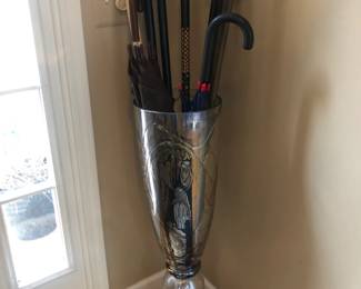 Large glass vase holding collection of walking sticks  