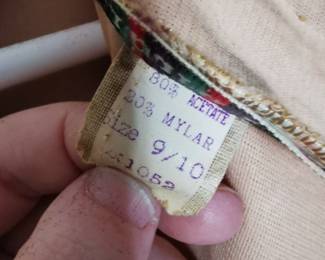 Fabric content tag detail of Barbara Field sleeveless gold lame a-line dress with french dart fitting details, zip back closure