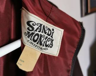 Tag detail of 1960s Sandi Monica California brown swing dress with a zip back, a funnel neck, and fur sleeve cuffs, Size 10