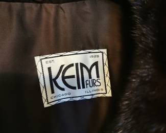 Tag detail of long luxurious vintage fur coat in a deep rich brown, featuring wide sleeves, a dramatic collar, and frog closures by Keim Furs Chicago Illinois