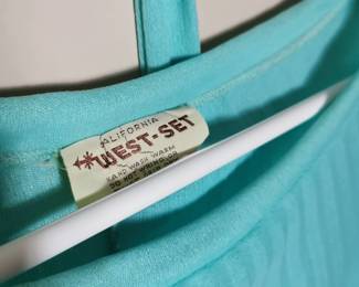 Tag detail of California West -Set aqua blue skirt and blouse set featuring short flutter sleeves, a matching belt, and a pleated skirt