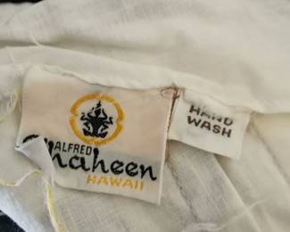 Tag detail of amazing vintage 1970s Shaheen Hawaii white halter dress featuring sunburst medallion designs in warm tones and black accents