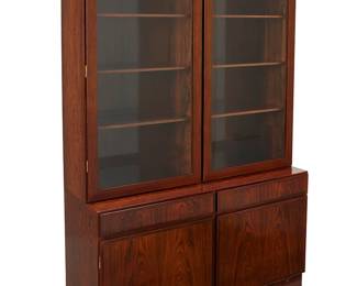 204
1960s; Denmark
An Omann Jun Møbelfabrik Bookcase And Model 3 Cabinet
Bottom console with paper tag to interior: Omann Jun A/S / Model Nr. 3; further stamped to verso: Danish Furnituremakers Control; upper console with paper label instructions applied to verso
The rosewood veneer teak wood bookshelf with brass hardware, comprising an upper console with two plate glass hinged doors revealing six shelves, above a lower console with two drawers and two hinged wood doors revealing an inner felt-lined drawer, 2 pieces
Upper: 47.25" H x 47.25" W x 12" D; Lower: 27" H x 47.25" W x 17" D
Estimate: $1,000 - $1,500