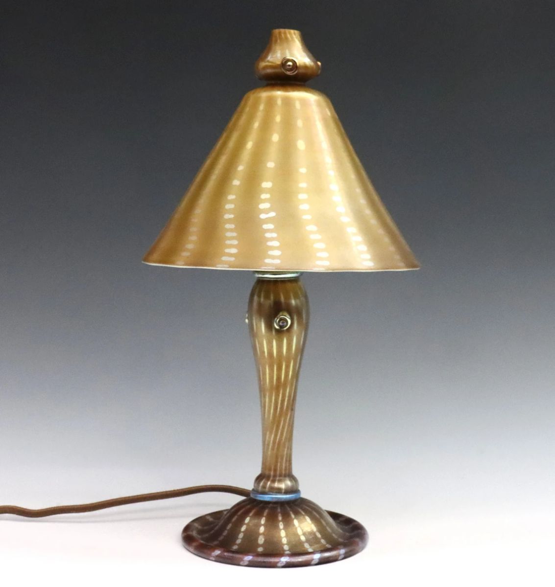 An early 20th century Tiffany Favrile Glass boudoir lamp.  Conical glass shade and baluster base with Gold/Amber Arabian pattern decoration having a repetitive dot design with applied circular prunts.  Shade signed "LCT" and base "L.C. Tiffany".  Slight surface wear.  7" diameter x 13 1/2" high overall.  

