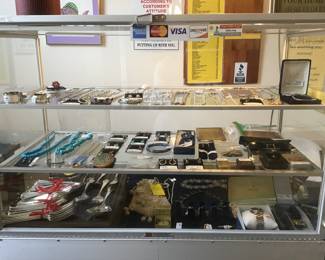 Showcase filled with sterling silverware, watches, jewelry, lighters etc.