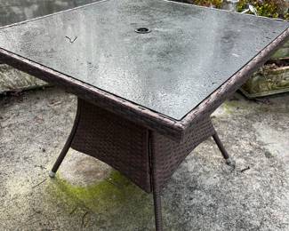 Glass top table with plastic wicker base