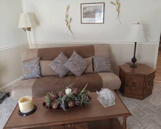 Futon with pillows, wood coffee table with storage, pair of matching wood endtables with storage. Floor lamp, decor