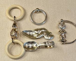 Collection of baby items, including Tiffany & Co. sterling teething ring (center top), A. Straus silver rabbit spoon (center middle), and Tiffany & Co. baby's spoon (center bottom)