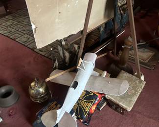 old plane, easel , artwork and fishing items in library floor