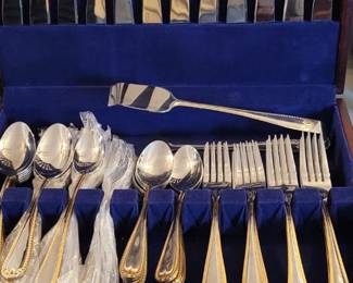 Stainless Steel Flatware Set, Made in China, in wooden, felt-lined box.  Includes 12 six-piece placesettings with dinner fork, dinner knife, salad fork, soup spoon, dessert spoon, iced-tea spoon and 12 additional serving pieces.  