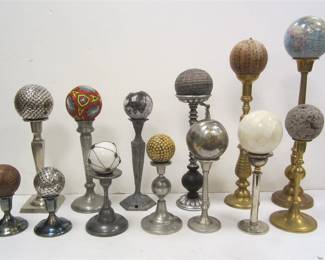  COLLECTION OF CANDLE HOLDERS AND BALLS DISPLAYED AS WE FOUND THEM IN THE HOME. BALLS OF ASSORTED METALS INCLUDING METAL, PAPER, WOOD, MINI GLOBES, AND EMBROIDERY. CANDLE HOLDERS ARE SILVER PLATE, BRASS AND PEWTER INCLUDING TWO ANTIQUE HOLDERS