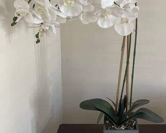 Artificial orchid in planter.
