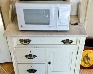 White Marble top cabinet with microwave oven.