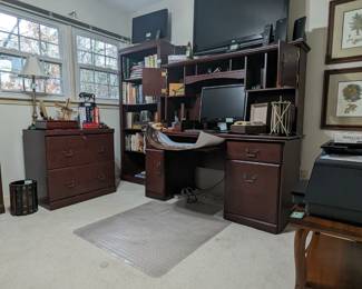 Office with desk, bookcases, filing cabinets. flat screen TV's, books and computers.