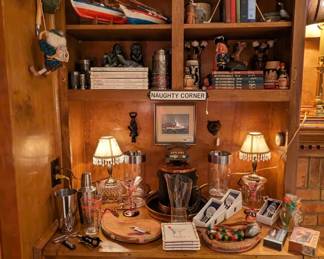 One of the built-ins, with wooden ship models, books (shock!) assorted bartending doodads, pair of small bookshelf lamps and a small, framed, hand-painted original watercolor.