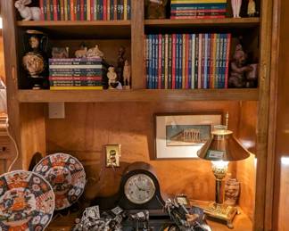 The other built-in, with large collection of "Automobile Quarterly" books, pair of model motorcycles, vintage camelback mantle clock, pair of Asian porcelain plates on stands,  adjustable brass lamp and a small, framed, hand-painted original watercolor.