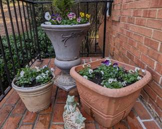 Left of front door faux cast iron (plastic) planters with freshly  planted pansies and violas.
