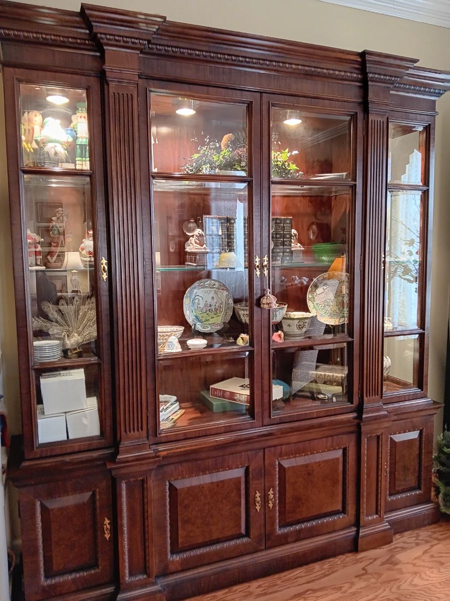 Lighted, mahogany, display cabinet containing antique books, oriental items, nutcrackers.
