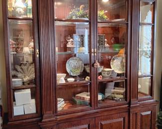 Lighted, mahogany, display cabinet containing antique books, oriental items, nutcrackers.