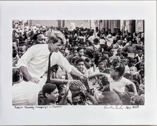 A photographic print of Senator Robert Kennedy during his 1968 campaign clasping the hand of young Sybil (Turner) Martin near the intersection of 12th Street and Clairmount in Detroit, Michigan. From the original negatives taken by Andrew Sacks, fused to foam board. Signed "Andrew Sacks" and dated "1968" lower right, titled lower left. Image 16 1/2 x 10 3/4" high, foam board 19 3/4 x 15 3/4" high overall.