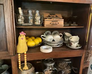 Hoosier cabinet items - chicken, bowl with lemons, dishes, wire basket, carton  for eggs, red boopie glasses and a long legged chicken!