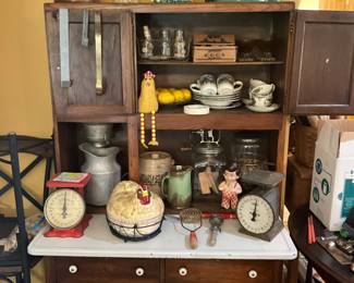 Another picture of Hoosier Cabinet - items inside include two vintage scales, large “Hen” 2 piece container in wire basket, vintage   B b