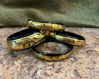 4 black bracelets with gold design. Feels like hard plastic. From Thailand.