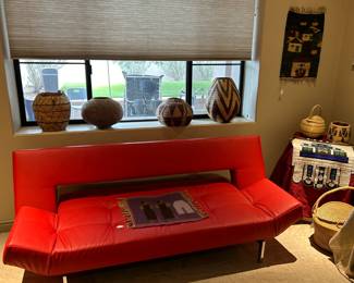 Red faux leather couch converts to a twin sleeper bed. Plus more Lesotho baskets and beadwork.