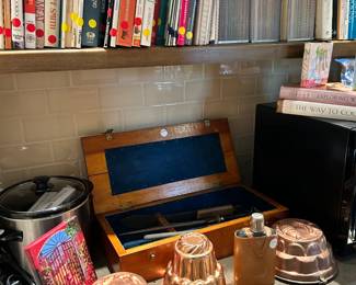 Vintage cutlery, copper molds, flask, and cookbooks.